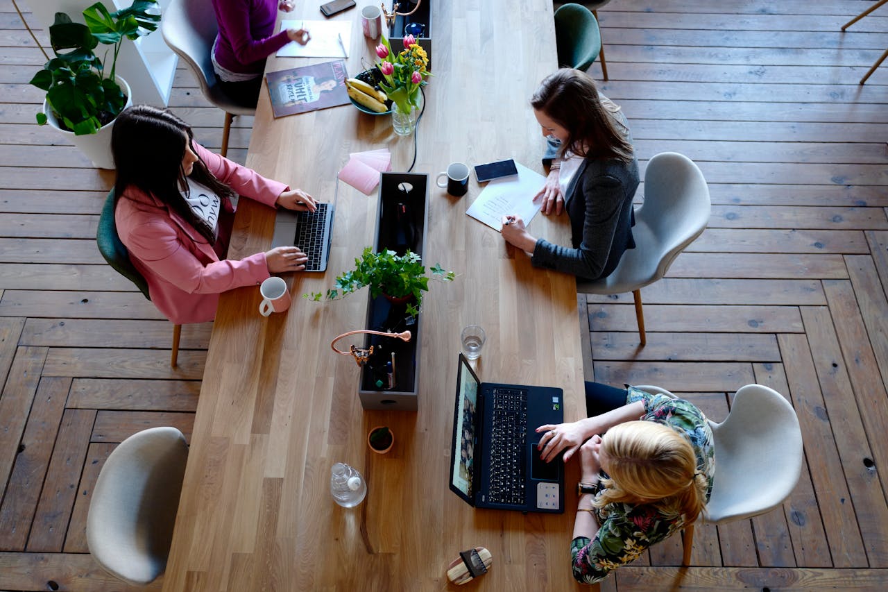 Nosotros Overhead view of diverse women professionals working in a modern office setting, fostering collaboration and teamwork.