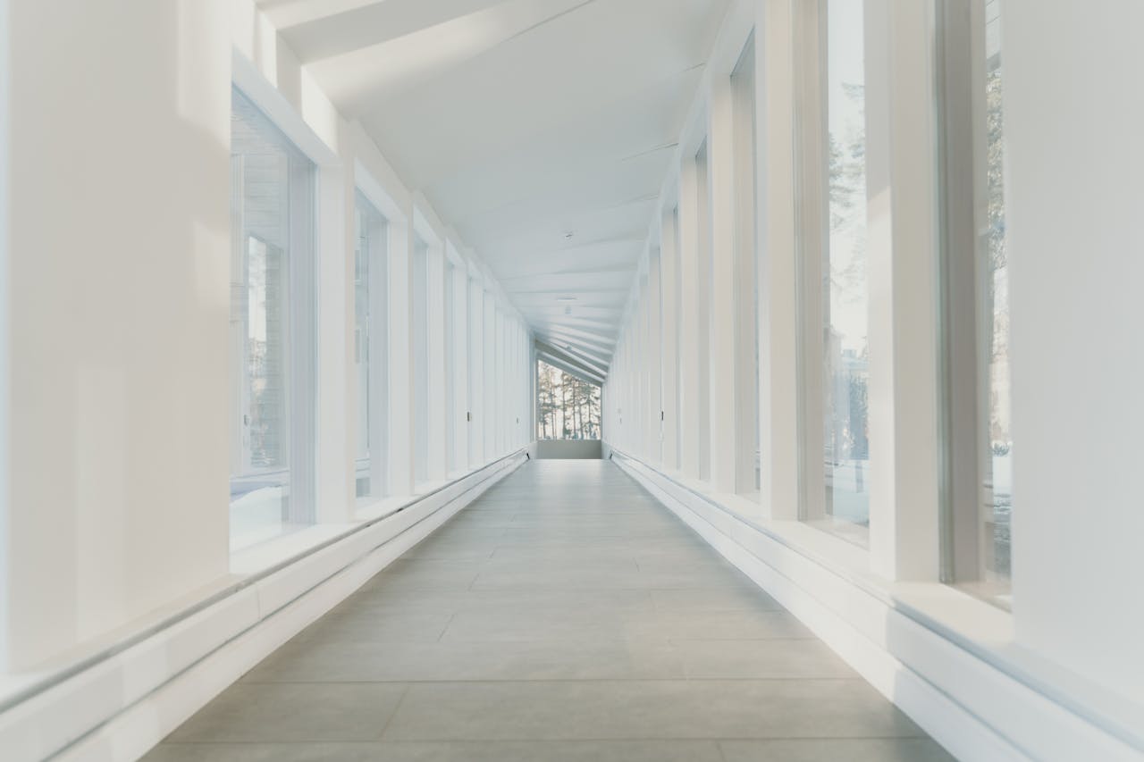 Productos y Servicios Bright and airy modern hallway with large glass windows showcasing minimalist design.